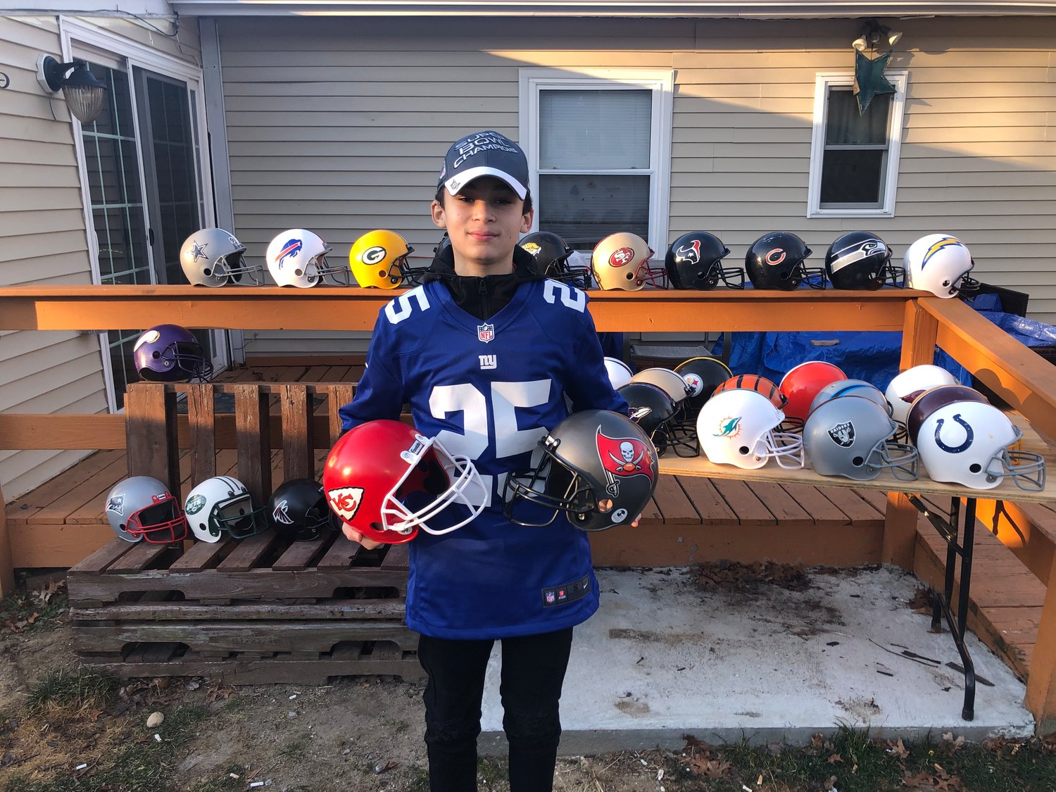 Donovan with his helmet collection holding this year’s Super Bowl teams, the Buccaneers and the Chiefs.